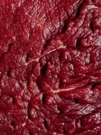 Detailed view of raw beef texture showcasing its red color and natural patterns.